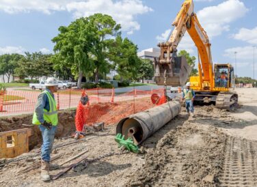 crew with excavator lifing pipe with chains at Rochelle Blvd